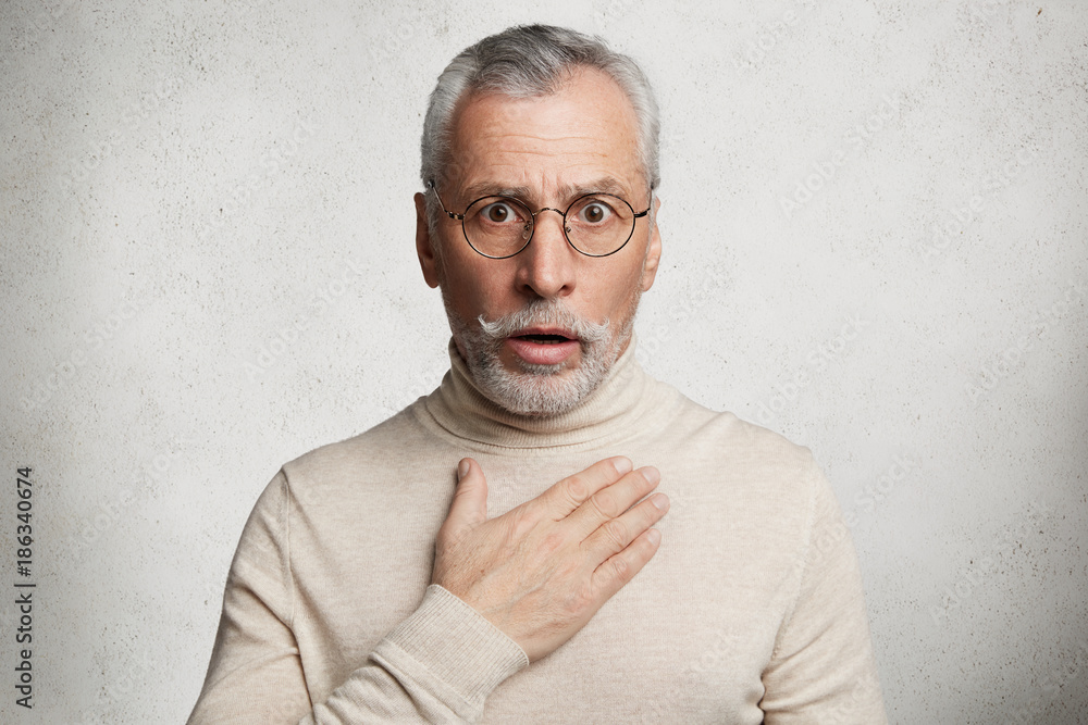 Frightened shocked bearded man has beard stares at camera with bated ...