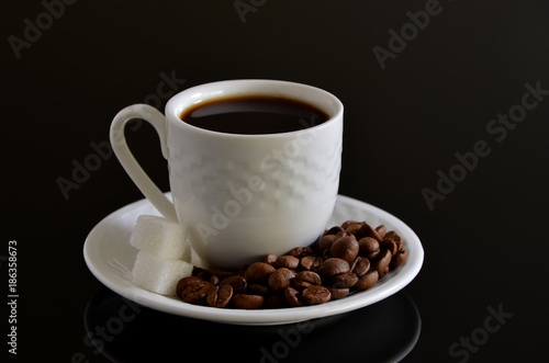 Hot Coffee cup with Coffee beans on the black table