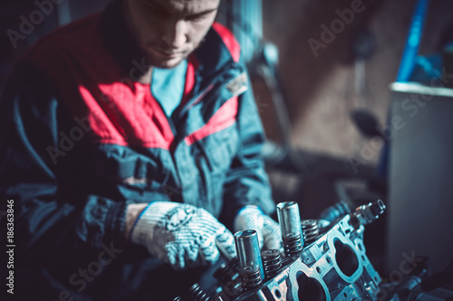 Billede på lærred The young auto mechanic dismantles the opposing engine.