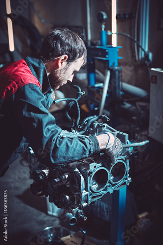 The young auto mechanic dismantles the opposing engine.