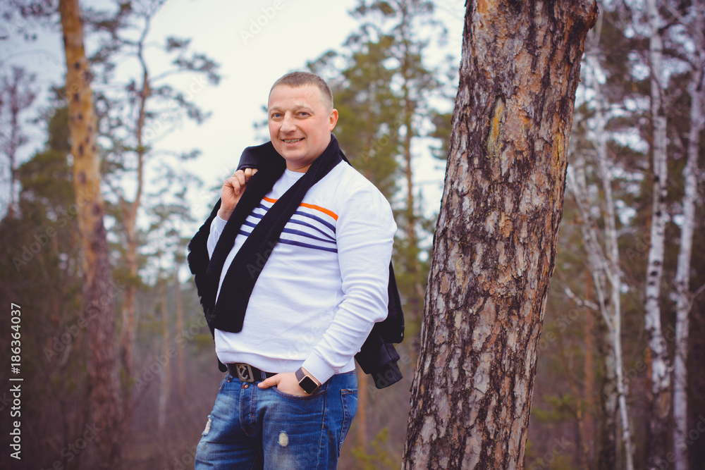 Portrait of a middle age man in warm clothing at forest on a cold day. Fashion handsome elegant man wearing black coat in winter day over trees forest background Portrait of a middle age man in warm clothing at forest on a cold day. Fashion handsome elegant man wearing black coat in winter day over trees forest background