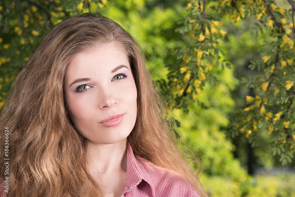 Horizontal portrait of a beautiful young woman with her hair in nature. Long natural hair, light makeup, pink shirt Horizontal portrait of a beautiful young woman with her hair in nature. Long natural hair, light makeup, pink shirt