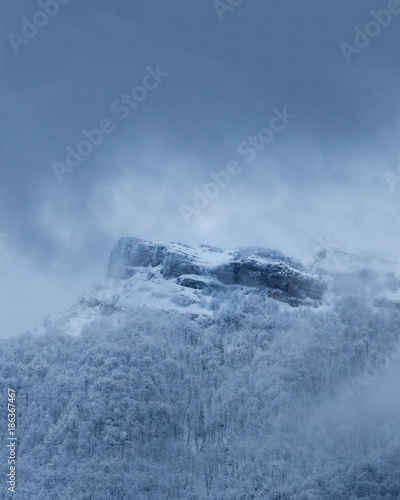 Dramatic winter mountain scenery at Slovakia, Mala Fatra, Klak. Snow storm closing in on frozen forests and hiding Klak peak to cold winter mist.