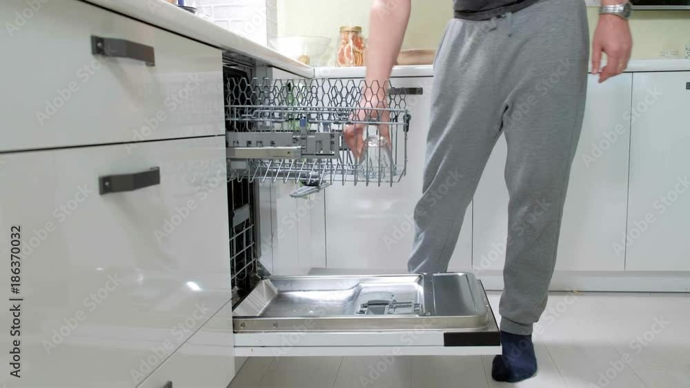 A man puts dirty dishes in the dishwasher A man puts dirty dishes in the dishwasher