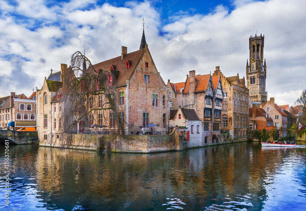 Famous Belfry tower and medieval buildings along a canal in Bruges, Belgium