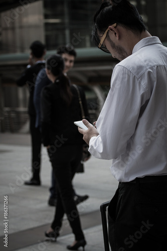 businessman walking outdoor in the city holding a smartphone
