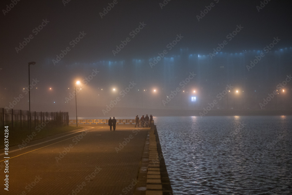 The people walking near the night river. Minsk. Belarus