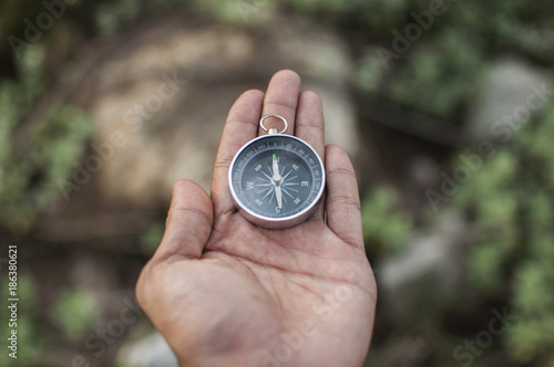 Compass in the hand against mountain. Adventure end travel background.