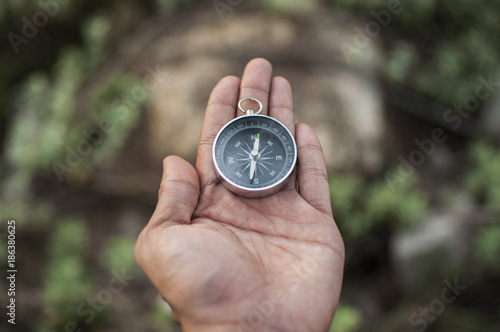 Compass in the hand against mountain. Adventure end travel background.