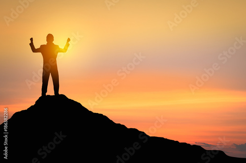 Success and winner concept, Silhouette of man standing and showing hand to celebrate in sunset and twilight..