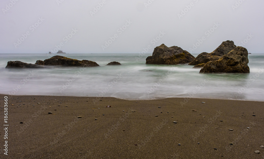 Obraz premium Sand and Smooth Waves Among Rocks