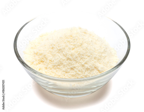 grated Parmesan cheese in glass bowl on white background