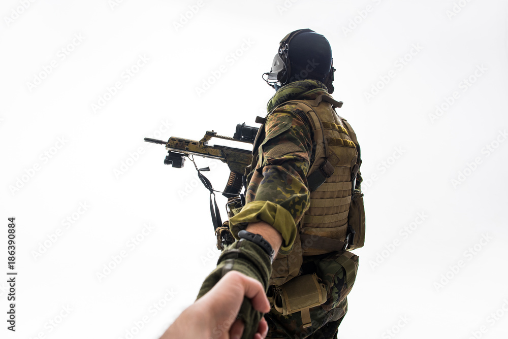 Defender keeping man by hand while turning back to camera. Military and help concept. Isolated Defender keeping man by hand while turning back to camera. Military and help concept. Isolated