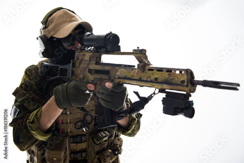 Portrait of calm soldier looking at sniper scope while keeping assault rifle in hands. Military concept, Isolated