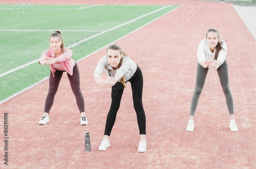Three girls doing aerobic exercises at the football stadium