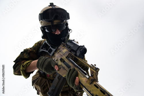 Portrait of serious defender in helmet and balaclava keeping assault rifle. War concept. Isolated