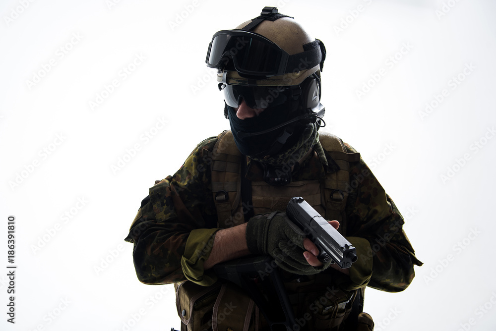 Portrait of stern soldier wearing uniform while holding modern pistol in hands. Military concept. Isolated Portrait of stern soldier wearing uniform while holding modern pistol in hands. Military concept. Isolated