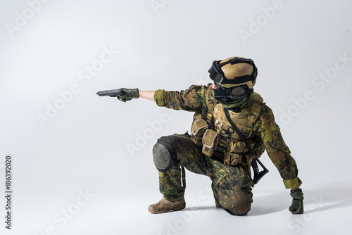 Side view severe soldier firing with pistol while wearing balaclava and helmet. War concept. Copy space