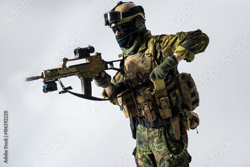 Side view severer peacemaker shooting assault rifle while taking machine gun clip from pocket. Military concept. Isolated