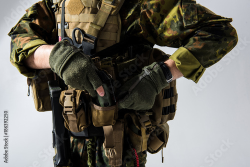 фотографія Close up soldier arms putting bombshell in special pocket in bulletproof vest