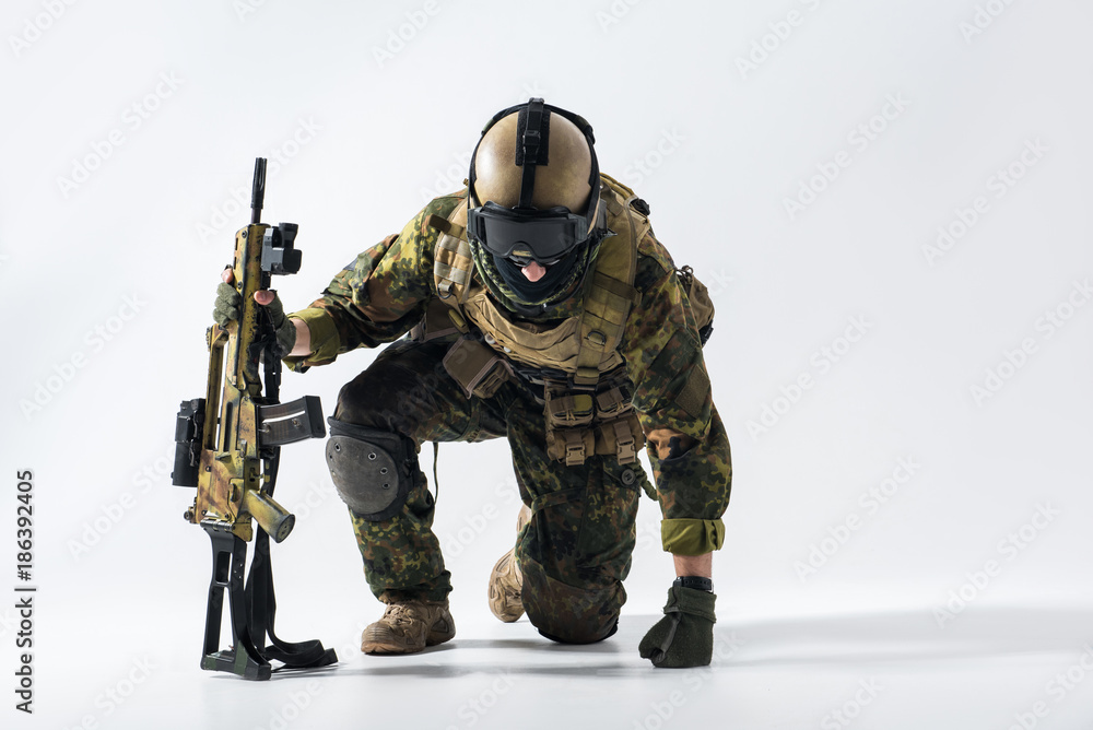 Portrait of stern defender rising from knees while leaning on weapon. Profession concept Portrait of stern defender rising from knees while leaning on weapon. Profession concept