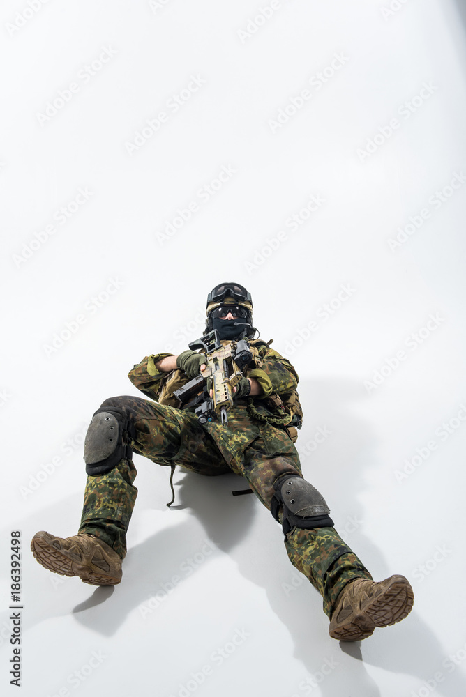 Full length portrait of grave defender lying on floor while shooting with assault rifle. Protection concept. Copy space Full length portrait of grave defender lying on floor while shooting with assault rifle. Protection concept. Copy space