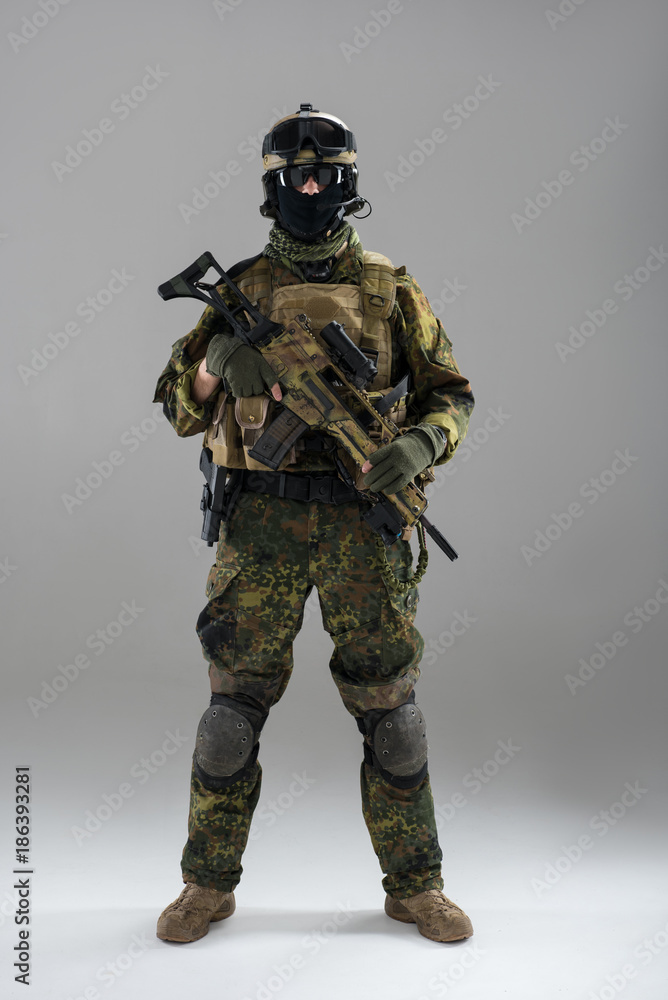 Full length portrait of stern soldier keeping assault rifle in hand. Army concept Full length portrait of stern soldier keeping assault rifle in hand. Army concept