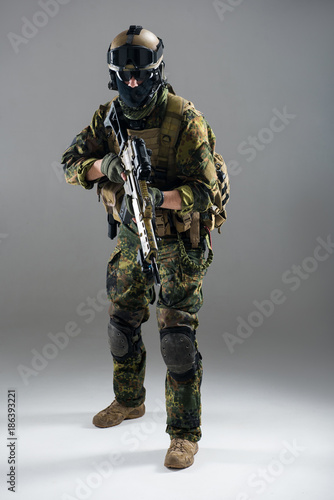 Full length portrait of serious man keeping assault rifle in hand. Army concept