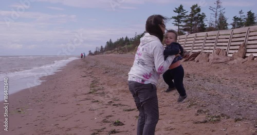 Grandmother pickd up crying toddler on beach - slow motion photo