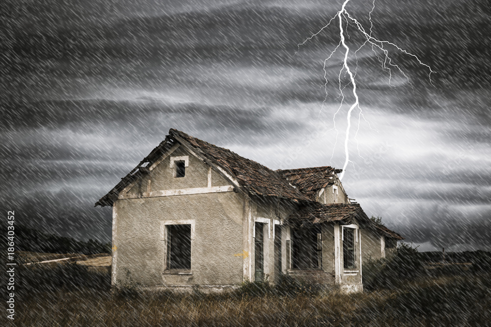 a storm with rain and a thunderbolt over a scary old abandoned house in