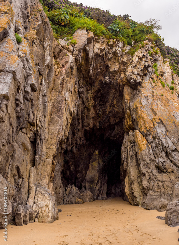Caves formed in the amazing rocks in the cliff face at Tenby South Beach, Tenby, Wales, UK Caves formed in the amazing rocks in the cliff face at Tenby South Beach, Tenby, Wales, UK