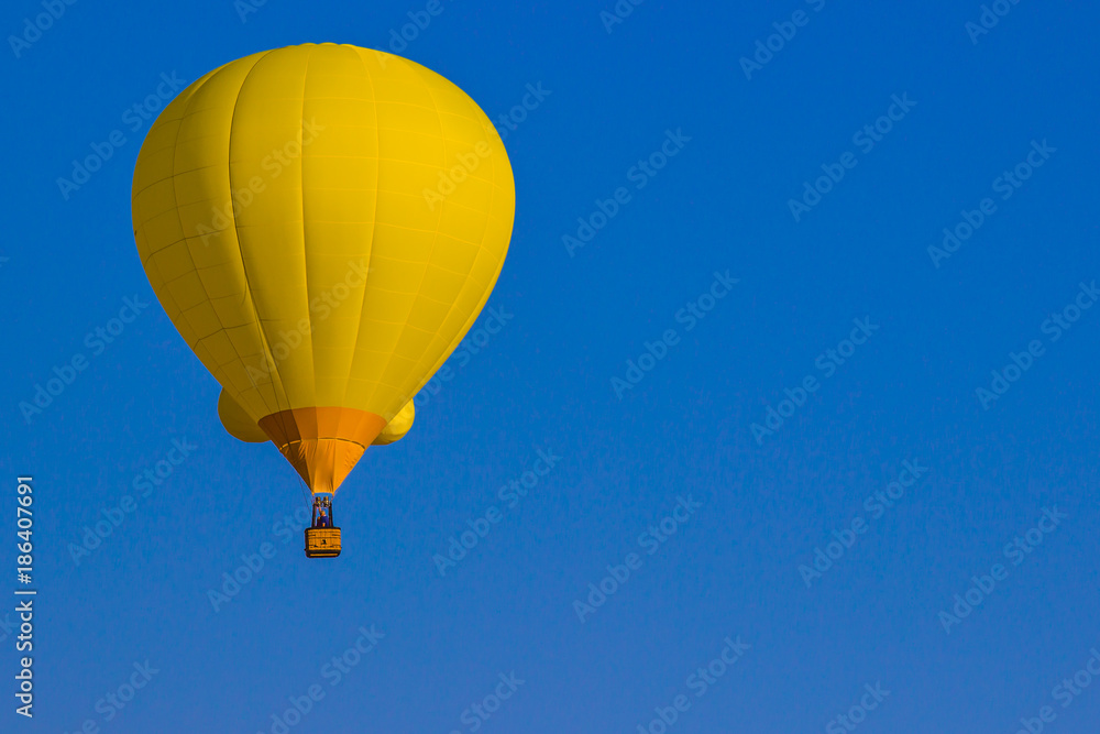 Naklejka premium Yellow Hot Air Balloon Against Blue Sky Background