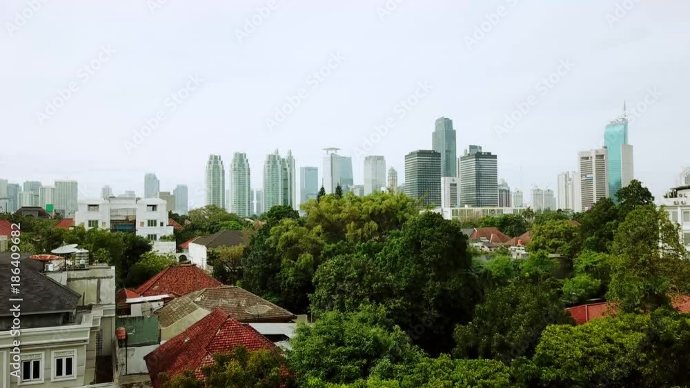 JAKARTA - Indonesia. December 22, 2017: Bird view of residential houses with skyscrapers background from a drone flying upward in Jakarta. Shot in 4k resolution JAKARTA - Indonesia. December 22, 2017: Bird view of residential houses with skyscrapers background from a drone flying upward in Jakarta. Shot in 4k resolution