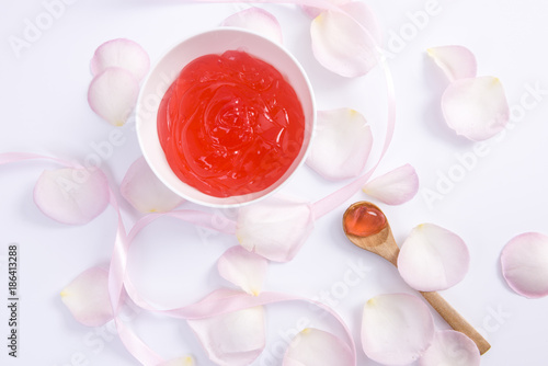 Pink rose flower petals and red cream on white background for beauty cream. Beauty cream 