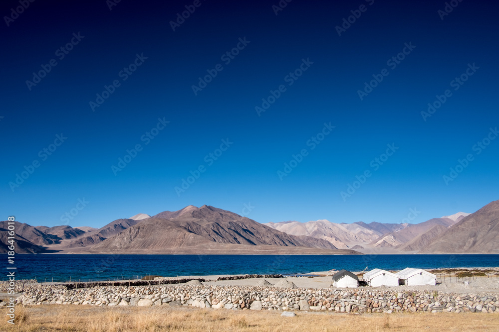 Fototapeta premium Landscape image of Pangong lake with small camps , mountains view and blue sky background