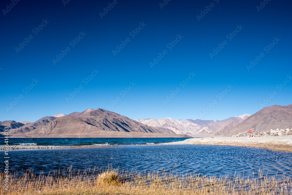 Landscape image of Pangong lake with mountains view and blue sky background
