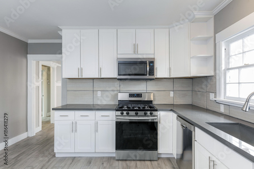 Kitchens in white new, with granite counter-tops, stove and stainless steel refrigerator. photo
