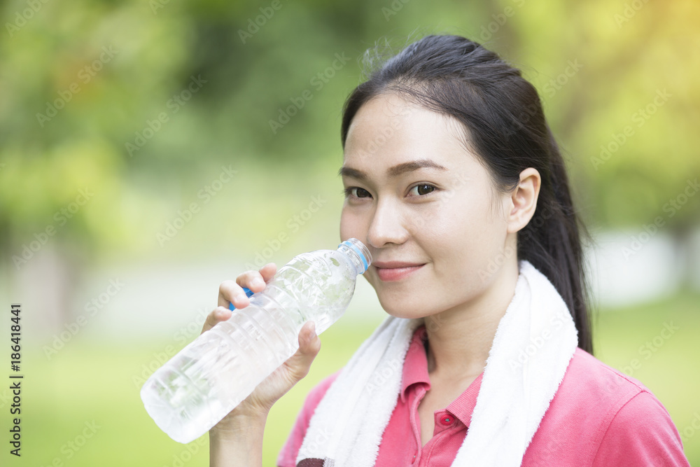 sporty woman drinking water from a bottle after jogging or running, sport and healthy concept sporty woman drinking water from a bottle after jogging or running, sport and healthy concept