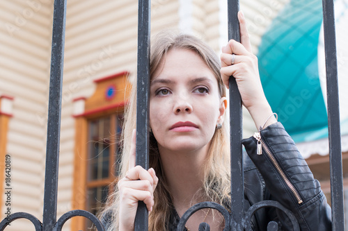 Portrait girl with blond hair near lattice