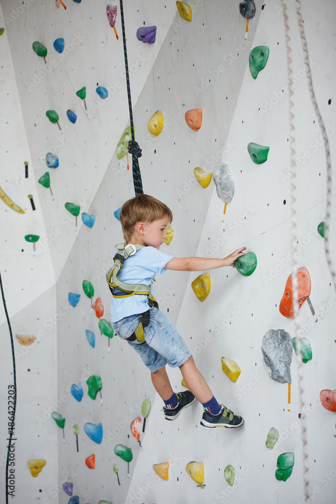 Fototapeta premium Child climbing on a high wall