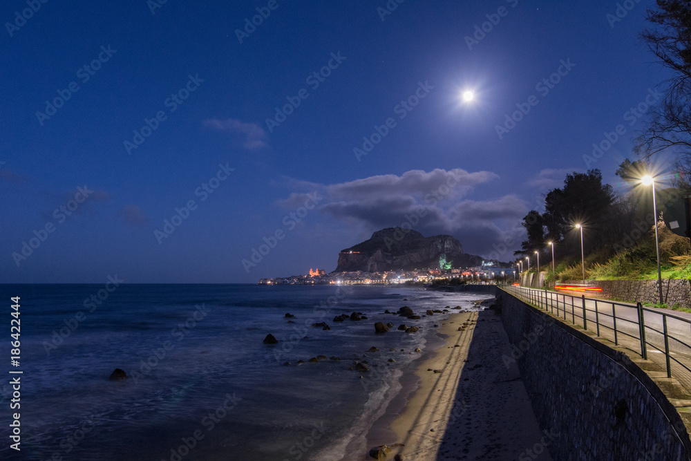 Fototapeta premium Vista notturna della spiaggia di Cefalù con la cittadina sullo sfondo, Sicilia