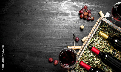 Wine background. Red wine in an old box with a corkscrew.