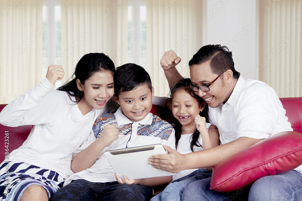 Happy family using a tablet together at home Happy family using a tablet together at home