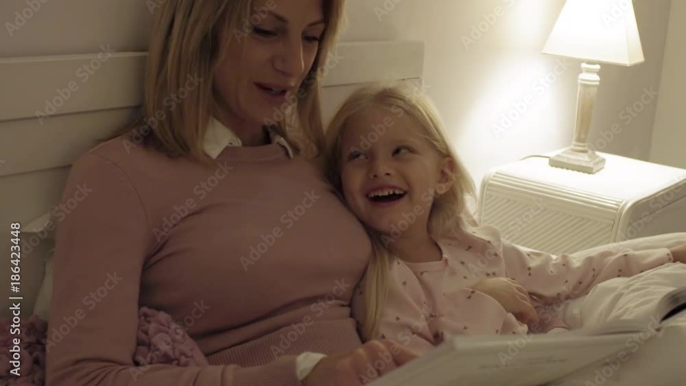 Mother and daughter at home at bedtime reading story Mother and daughter at home at bedtime reading story