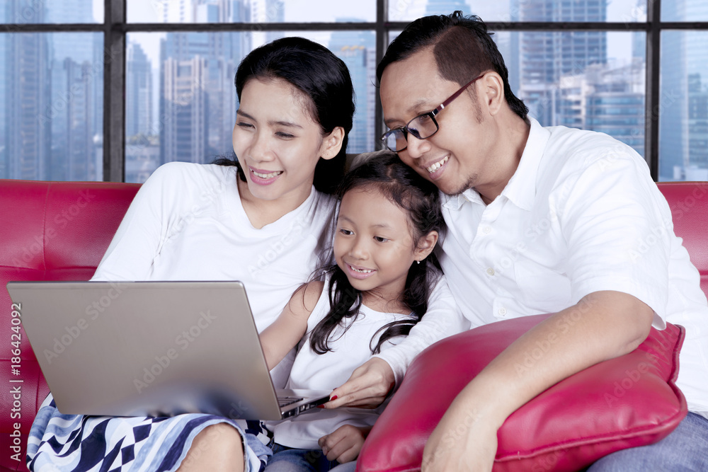 Fototapeta premium Cute child with parents using a laptop