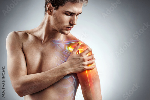 Man holding his injured shoulder that's highlighted in red. Medical concept. photo