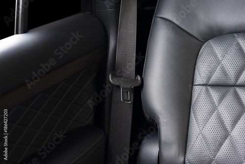 Part of black  leather car seat detail with focus on safety belt locks, modern luxury car interior © gargantiopa