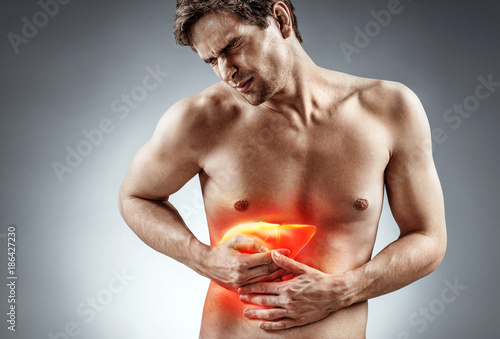 Cirrhosis of the liver. Photo of man holding his hand in area liver and grimacing in pain on grey background. Medical concept photo