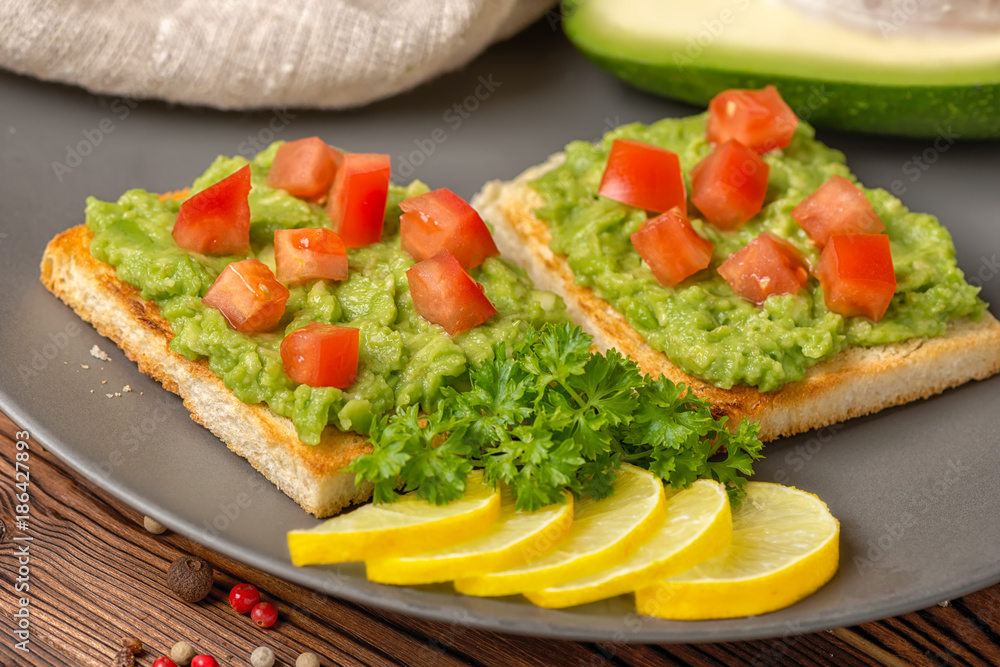 top down of sandwiches with latin american sauce guacamole avocado, diced tomatoes and toast decorated alligator pear fruit, sliced lemon on plate, parsley, vegetarian food top down of sandwiches with latin american sauce guacamole avocado, diced tomatoes and toast decorated alligator pear fruit, sliced lemon on plate, parsley, vegetarian food