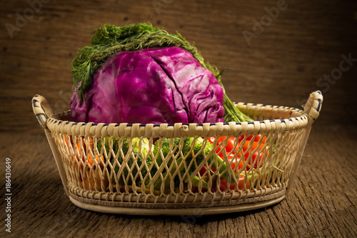 red cabbage. baby tomatoes. dill. in wood basket. on wooden kitchen. morning. sunset photo